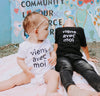 Viens Avec Moi white onesie with black screen printed logo. Black Viens Avec Moi Kids Tee in black cotton with a white screen print front.