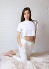 White jogger pants made from lightweight cotton with a drawstring waist and cinched ankle. 