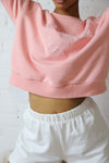 Cozy pink crewneck sweater made from eco-friendly fabric with an embroidered circle 'Viens AVec Moi' logo on the front.