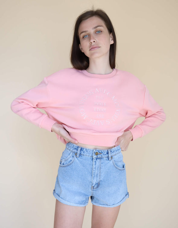 Cozy loungewear, pink crewneck sweater with drop shoulder and embroidered front design paired with denim shorts for a laid back, urban look.