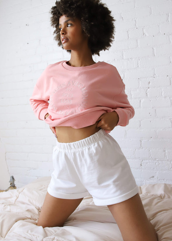 Pink cropped crewneck sweater with embroidered front design paired with white shorts for a cozy loungewear set.
