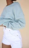 Closeup of the dropped shoulder detail on the seafoam green crewneck sweater made from eco-friendly fabrics.