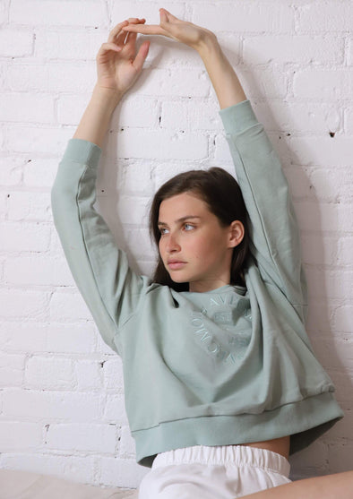 The seafoam crewneck sweater has a dropped shoulder. tonal embroidered design on the front, and a relaxed fit making it the perfect loungewear piece.