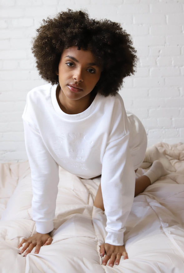 Cropped white drop sleeved crewneck sweater with a tonal white embroidered logo on the front and the perfect cozy fit.