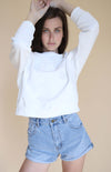 Cropped white crewneck sweater with dropped shoulder detail and white embroidered logo on the front.