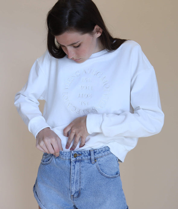 White crewneck Lakeside Crew sweater styled with denim shorts for a relaxed, urban look.
