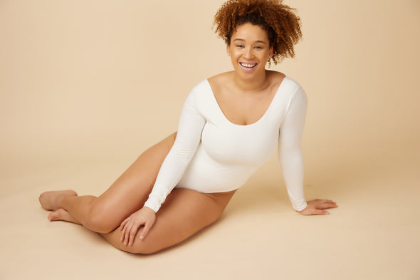 A white long sleeve bodysuit with a body hugging fit is a capsule wardrobe essential because it can be worn casually or dressed up.