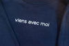 White 'viens avec moi' logo on the navy blue cozy crew neck sweater with an oversized fit.