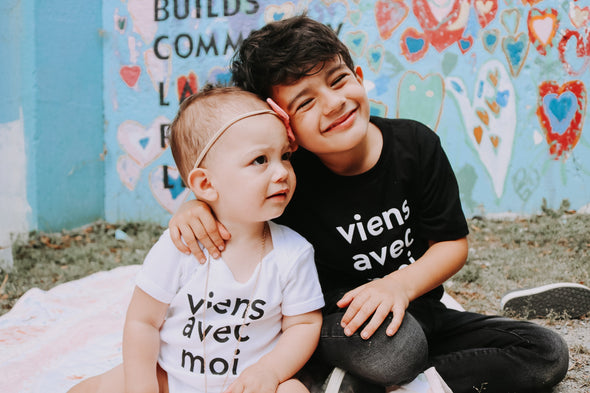 Viens Avec Moi Kids white onesie and Viens Avec Moi Kids tee in black. 100% cotton screen printed tops.